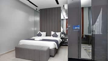 Un dormitorio moderno con una cama grande, un banco gris, un armario y un espejo.