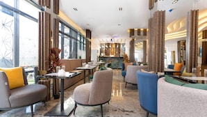 Um interior moderno com assentos dispostos, área de bar e vista através de grandes janelas.