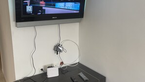A television mounted on a wall above a dark wooden entertainment unit.