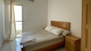 A bedroom with a bed, nightstands, a wooden wardrobe, and a curtain.