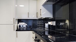 A modern kitchen with white cabinets, a black countertop, and stainless steel appliances. - 2 bedroom accommodation in Ambleside (Ambleside)