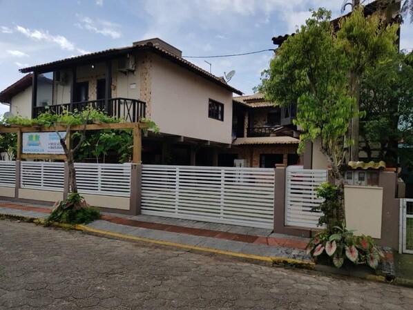 Un edificio de dos pisos con balcón, antena parabólica y un cartel.