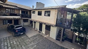 Een twee verdiepingen tellend huis met een pannendak, een balkon en een geparkeerde auto.
