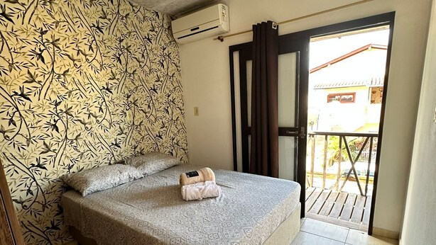 Een slaapkamer met een bed, een behang met patroon, een airconditioning en uitzicht op buiten.