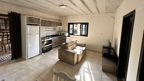 Een ruime keuken met moderne apparatuur, een eethoek met een houten tafel en een gezellige zithoek met een bank.