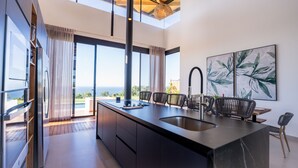 A modern kitchen with a large island, stainless steel appliances, and a view of the ocean. - Oceanvista Villa I Santa Teresa Beach  Brand New Oceanview Villa Gated Community (santa teresa)