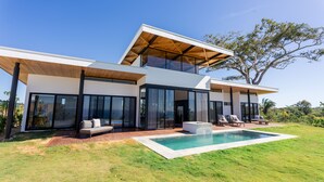 A modern two-story house with a large glass facade, a swimming pool, and outdoor seating. - Oceanvista Villa I Santa Teresa Beach  Brand New Oceanview Villa Gated Community (santa teresa)