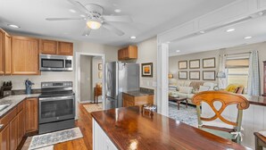 A modern kitchen with wooden cabinets, stainless steel appliances, and a wooden dining table. - Sunshine Manor (New Bern)