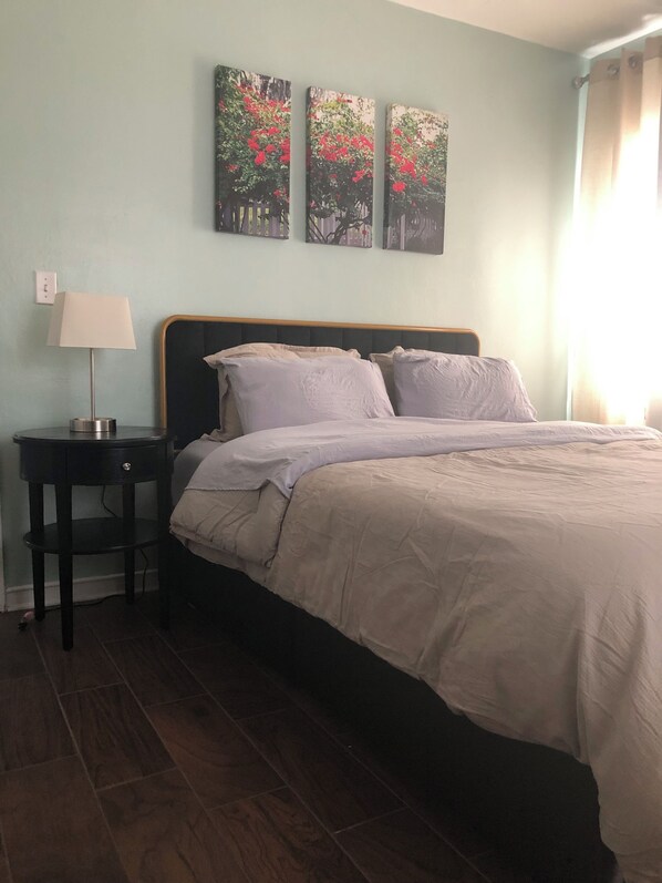 Un dormitorio con una cama, una mesita de noche, una lámpara y tres cuadros colgados en la pared.