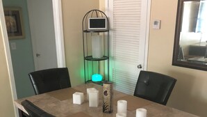 Comedor con una mesa rectangular, cuatro sillas y un candelabro decorativo con luz azul turquesa.
