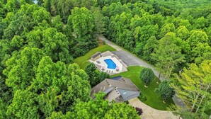 An aerial view of a residential property with a swimming pool, a covered patio, and a well-maintained lawn. - Welcome to “Relaxing on the Cumberland” – Your Perfect Cozy Escape (Burnside)