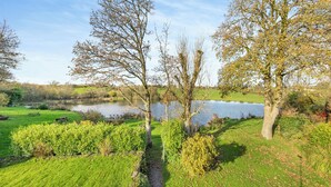 A serene park with a pond, trees, and a picnic area. - Ty Teiliwr - UK45719 (Tyn Y Gongl, near Benllech)