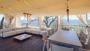 A covered outdoor seating area with a large sectional sofa, a dining table, and chairs. - Villa Paradiso–Villa with private pool, Umbria (Trestina)