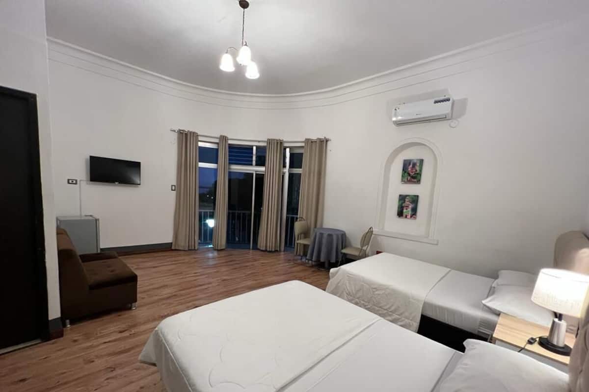 A hotel room with two beds, a TV, a desk, and a chair.