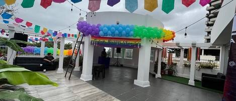 Un espacio interior con techo blanco y un arco de globos multicolores.