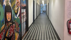 A hotel corridor with a checkered floor, a mural on the left, and a 'SALIDA' sign above a door. - HOTEL PERLA CENTRAL MALECON (Guayaquil)