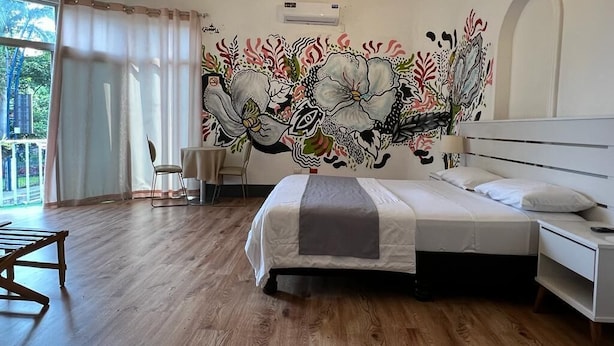 A bedroom with a large bed, a desk, a chair, and a mural on the wall. - HOTEL PERLA CENTRAL MALECON (Guayaquil)