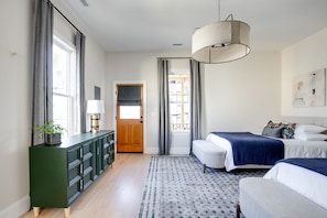 A modern bedroom with a large window, a green dresser, two beds with blue bedding, and a hanging light fixture. - Gorgeous new home in Churchill
(Richmond)