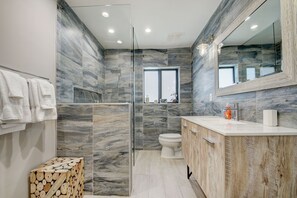 A modern bathroom with a glass-enclosed shower, a toilet, and a vanity with a mirror. - Beach House with Pool, Luxurious & Contemporary (West Palm Beach)