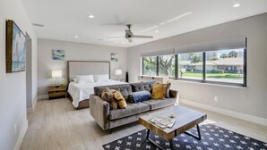 Un dormitorio moderno con cama, sofá, una mesa de centro y un amplio ventanal con vistas al exterior.