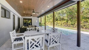 Un patio al aire libre con piscina, muebles blancos y techo de madera.