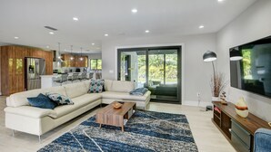 Una sala moderna con un sofá modular, una mesa de centro y un televisor de pantalla plana grande.