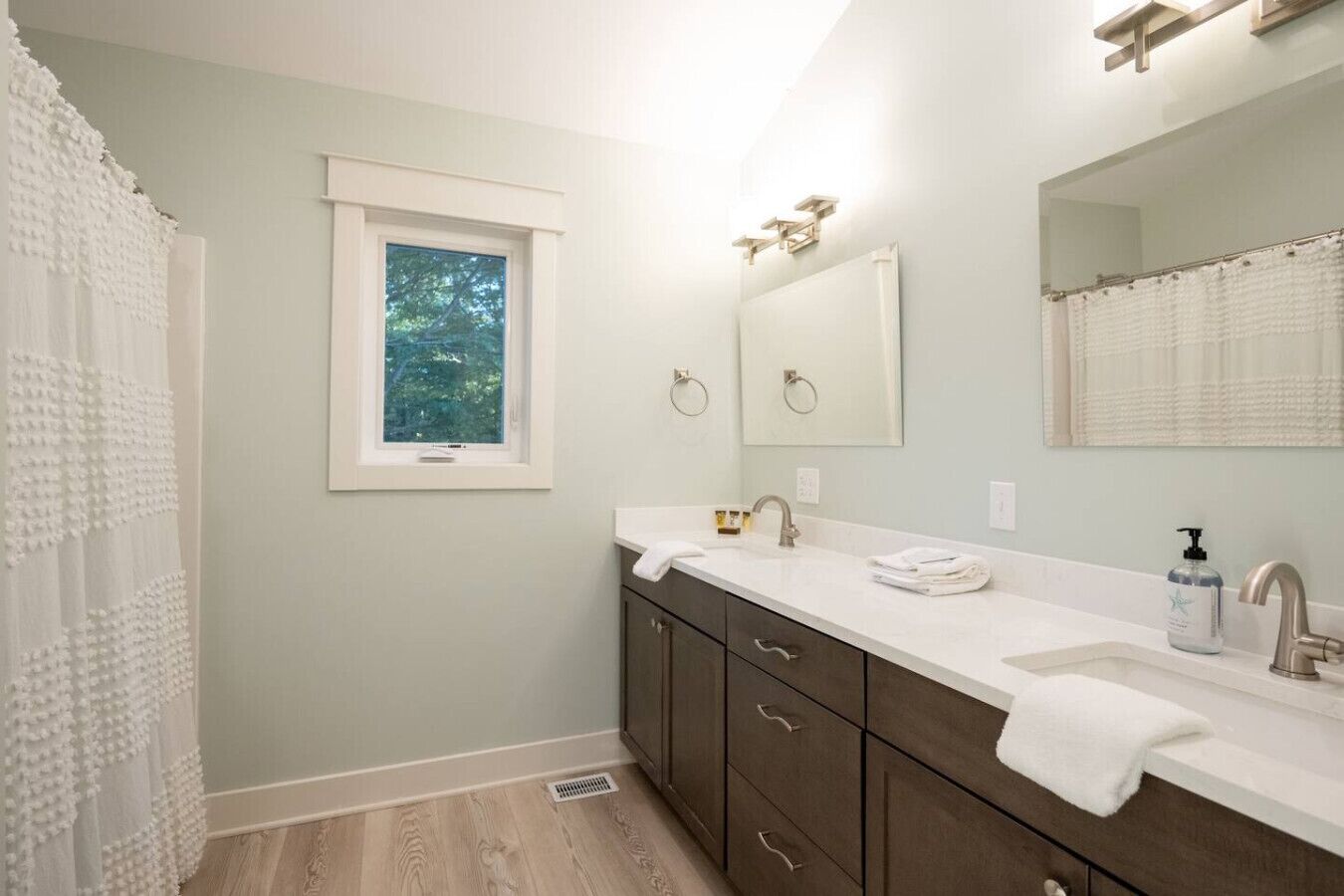Un baño con ventana, lavabo, espejo y cortina de ducha.