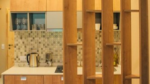Una cucina moderna con mobili in legno, zoccolo in piastrelle e una moka sul piano di lavoro.