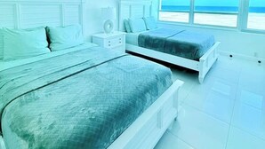 Ein Schlafzimmer mit zwei Betten, einem Nachttisch und einem Fenster mit Meerblick.