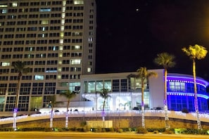 Un hôtel au design moderne, caractérisé par une façade incurvée et une façade extérieure illuminée de couleur bleue.