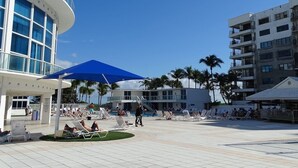 Ein Poolbereich eines Resorts mit Liegestühlen, einem blauen Sonnenschirm und Palmen.