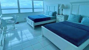 Ein Hotelzimmer mit zwei Betten, einem Schreibtisch, einem Stuhl und einem großen Fenster mit Blick.