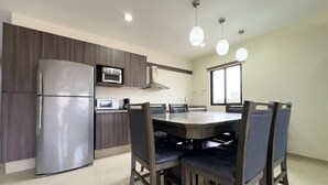 Una cocina moderna con refrigerador, horno, microondas y una mesa de comedor con sillas.