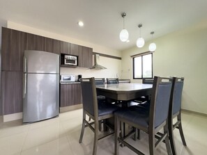 Une cuisine moderne équipée d’un réfrigérateur, d’un four, d’un four à micro-ondes et d’une table à manger avec des chaises.