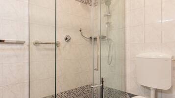 A modern bathroom with a glass-enclosed shower, a toilet, and a sink.
