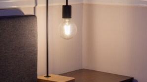 A modern bedroom with a single bed, a nightstand, and a wall-mounted lamp.