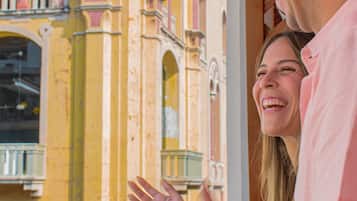 A building with yellow and pink columns, a balcony, and a person in a pink shirt.