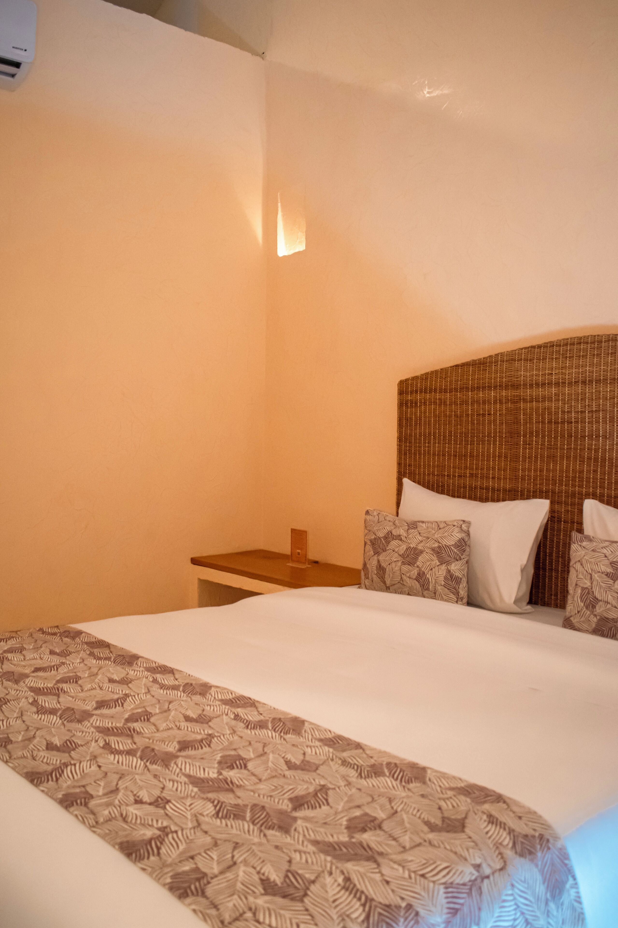 A hotel room with a large bed, a wooden nightstand, and a headboard with a patterned design.