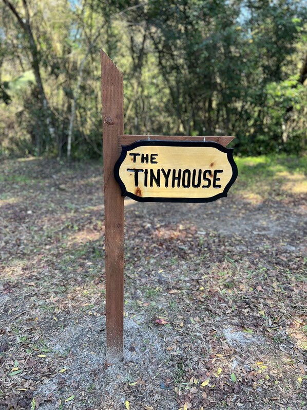 A wooden sign with the text "The Tinyhouse" in capital letters. - Tiny House on The Grove (La Crosse)