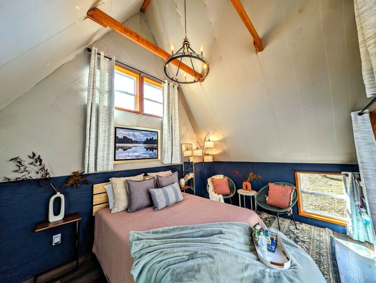 Un dormitorio acogedor con cama, mesitas de noche, una silla y una ventana con cortinas.