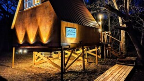 Ein Baumhaus mit einem Schild, das "Walnut Treehouse" zeigt, Holzstufen und einer Plattform.