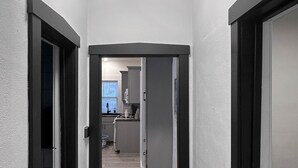 A hallway with a modern kitchen in the background, featuring a sink and cabinets. - The Bunga Glow: Modern, Cozy & Bright Near Downtown (Sioux Falls)