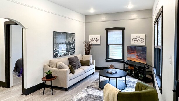 A modern living room with a sofa, coffee table, and a television. - The Bunga Glow: Modern, Cozy & Bright Near Downtown (Sioux Falls)