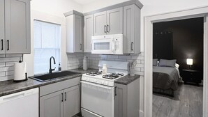 A modern kitchen with grey cabinets, a built-in microwave, and a gas stove. - The Bunga Glow: Modern, Cozy & Bright Near Downtown (Sioux Falls)