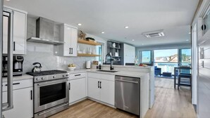 A modern kitchen with white cabinets, a stainless steel range, and a dishwasher.