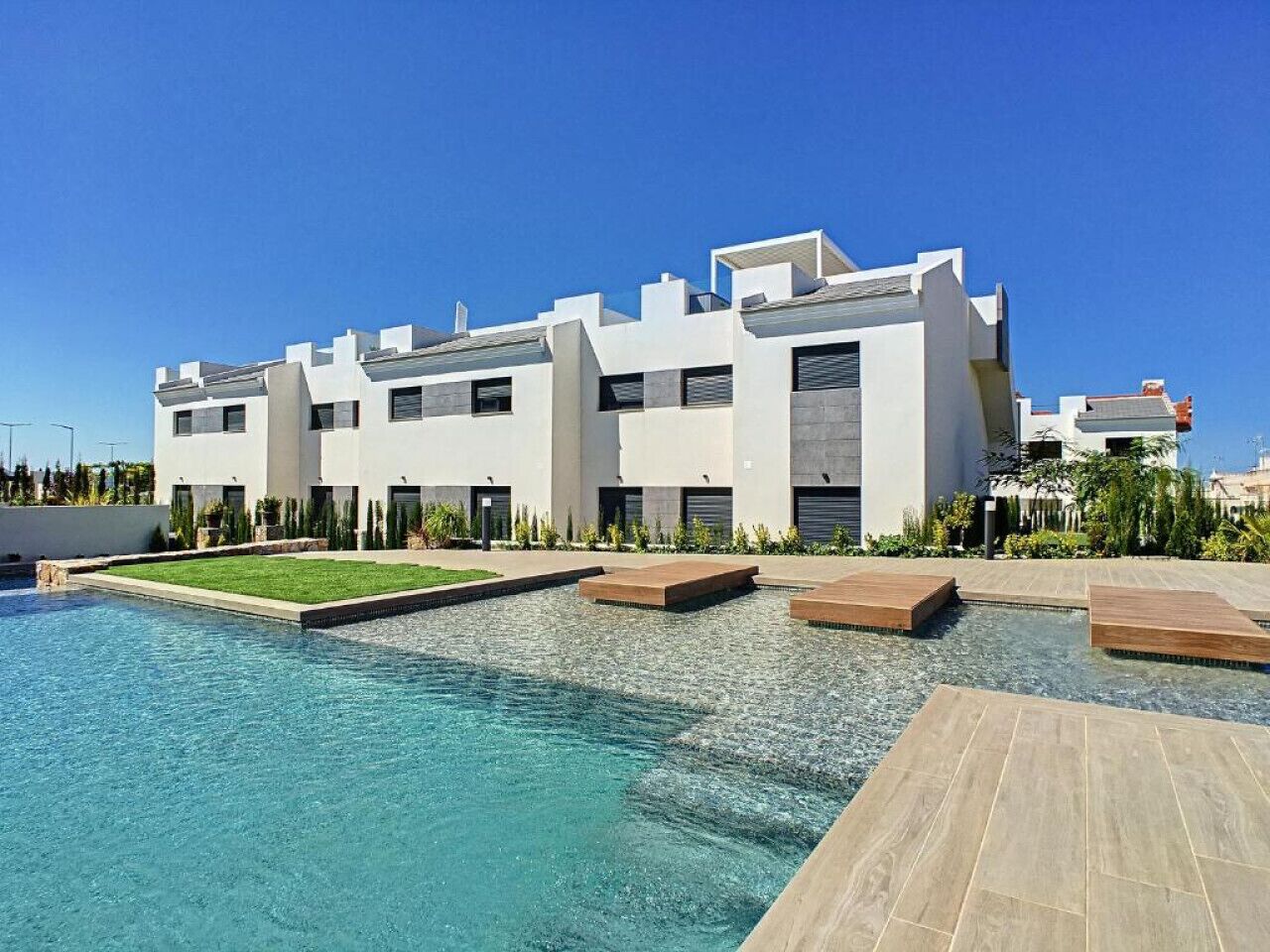 A modern building with a swimming pool and outdoor seating areas.