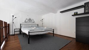 Una camera da letto con un letto, lampade ai comodini, un pavimento in legno e un tappeto grigio.