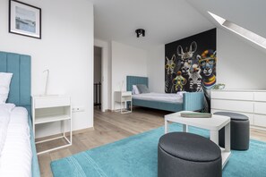 Un dormitorio moderno con cama, mesitas de noche, un escritorio, una silla, un sofá y un mural de colores.