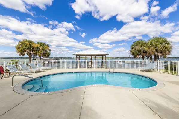A swimming pool with lounge chairs, a gazebo, and palm trees. - Amazing New Lagoon View Home (Gulf Shores)