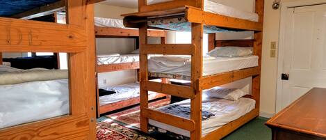 Une chambre avec un lit superposé à ossature en bois, un tapis à motifs et une porte.